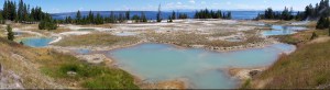 A panoramic view of the West Thumb Geyser Basin with Yellowstone Lake in the background.